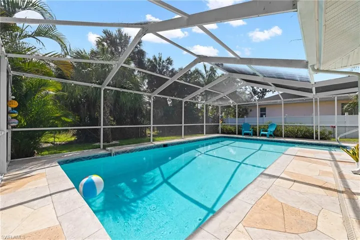 View of swimming pool with patio surround, glass enclosure, and a sunroom