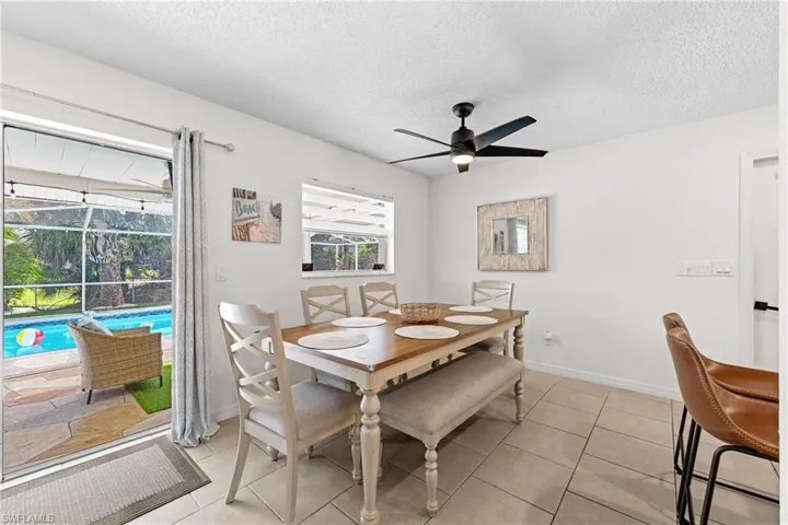 Dining space featuring ceiling fan, a textured ceiling, light tile patterned floors, and a sunroom