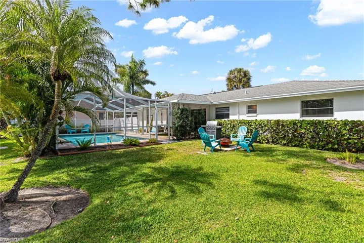 Rear view of property with an outdoor fire pit, a patio, a lawn, glass enclosure, and stucco siding