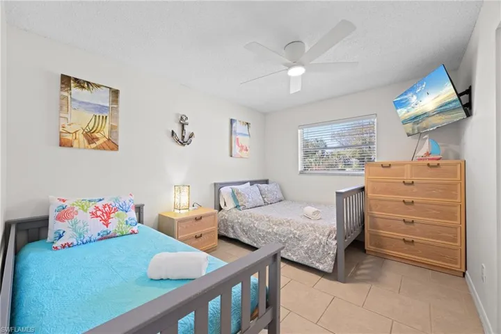 Bedroom featuring a textured ceiling, ceiling fan, and light tile patterned floors