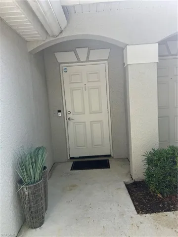 Doorway to property featuring stucco siding, an attached garage, and a tile roof
