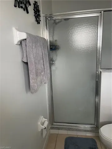 Full bathroom with tile patterned flooring, a shower stall, and toilet