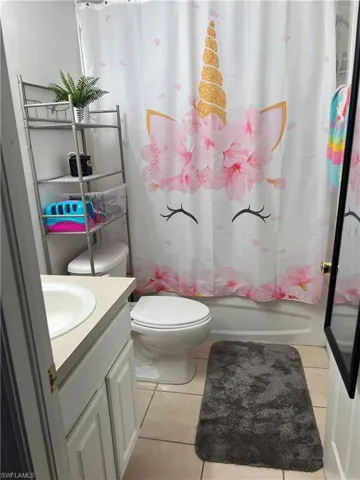 Bathroom with tile patterned floors, vanity, toilet, and shower / bath combination with curtain