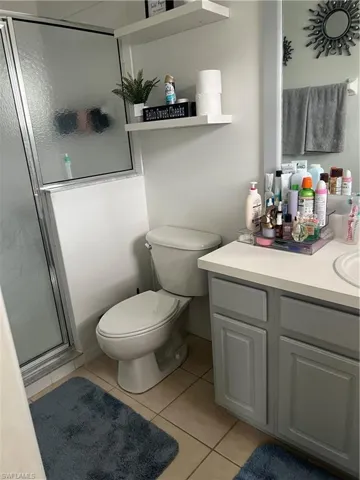 Bathroom with tile patterned floors, a stall shower, vanity, and toilet