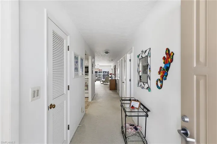 Hallway with a textured ceiling and light carpet