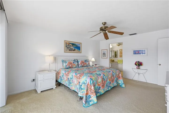 Bedroom featuring light colored carpet, a ceiling fan, and connected bathroom