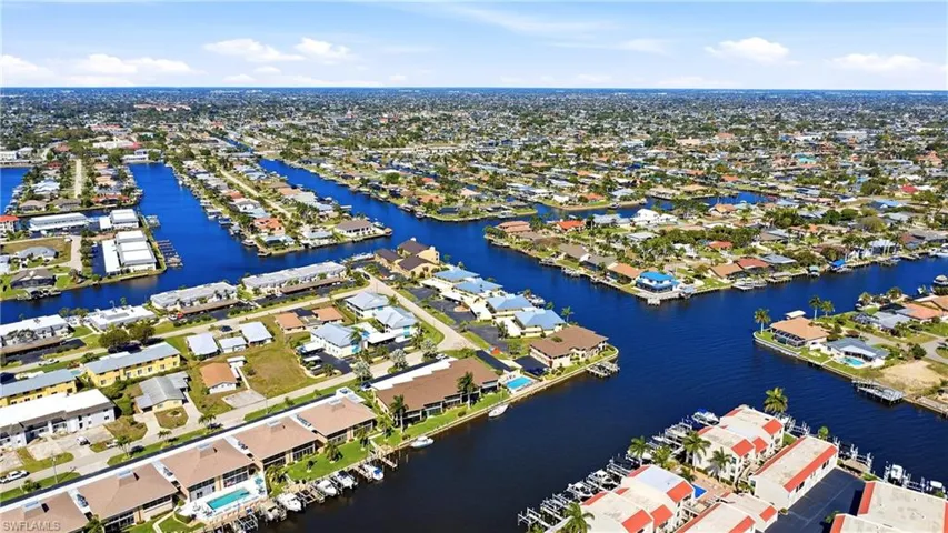 Aerial view of property and surrounding area featuring nearby suburban area and a nearby body of water