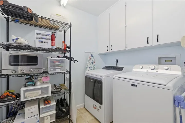 Laundry room featuring washing machine and dryer, cabinet space, and light tile patterned floors