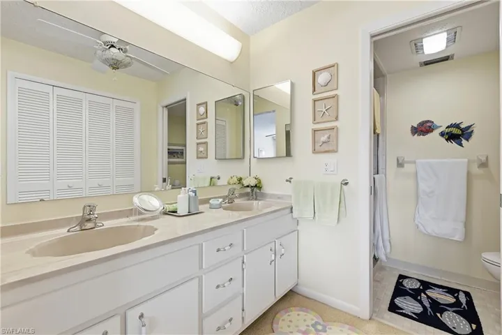 Full bath featuring double vanity, a shower stall, a closet, and ceiling fan