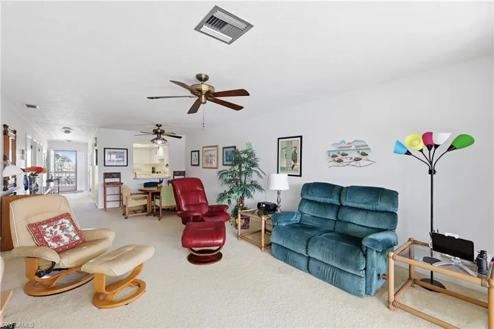 Living area with light colored carpet and a ceiling fan