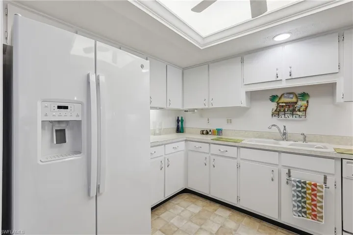 Kitchen with white appliances, light countertops, and white cabinetry