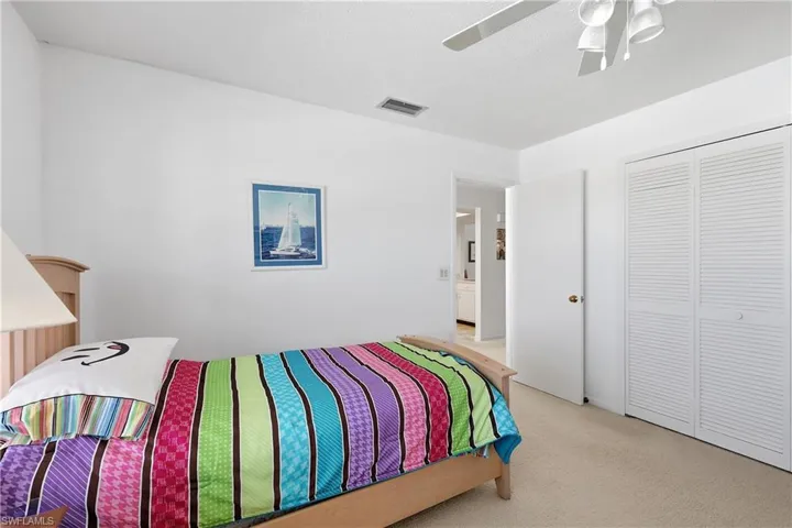 Bedroom featuring light carpet, a ceiling fan, and a closet