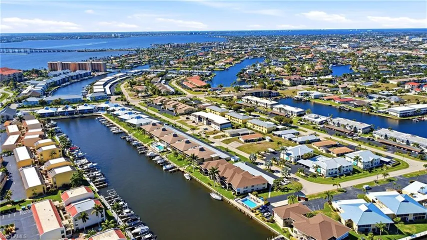 Aerial view of property and surrounding area featuring a nearby body of water and nearby suburban area