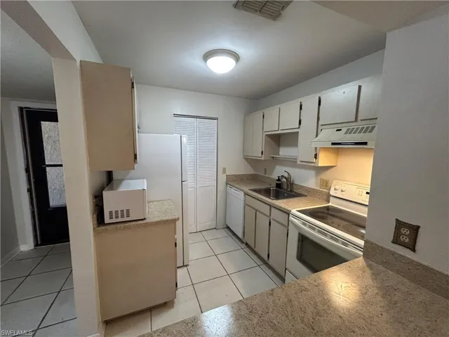 Kitchen featuring white appliances, exhaust hood, light countertops, and light tile patterned floors