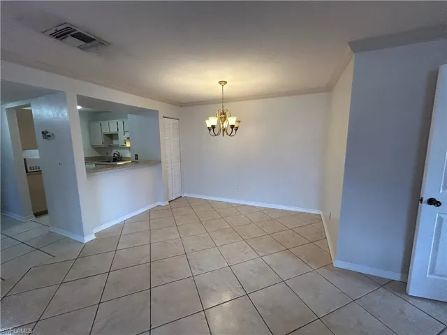 Unfurnished dining area with crown molding, hanging lights, and light tile patterned floors