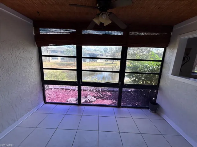 Unfurnished sunroom with a ceiling fan and a water view