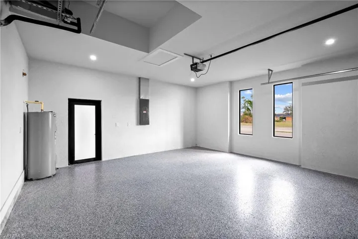 Garage featuring a garage door opener, electric panel, and water heater