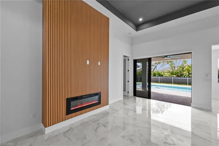 Unfurnished living room with a raised ceiling and ceiling fan