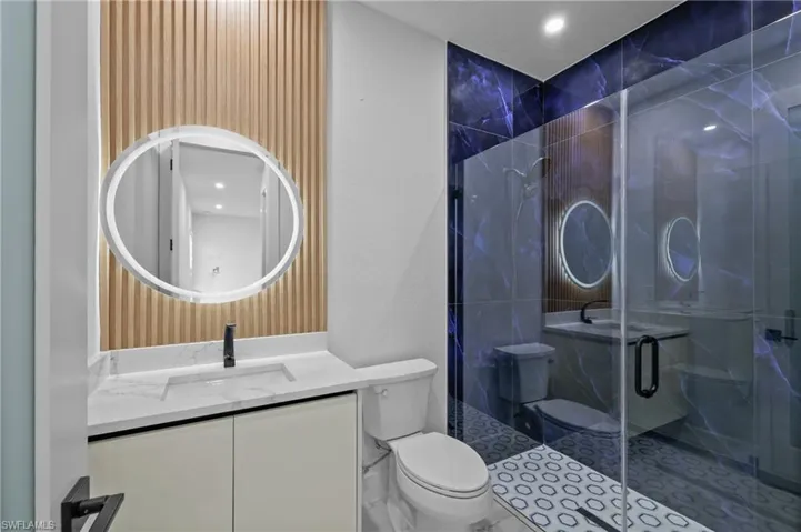 Bathroom with vanity, toilet, and a shower with door