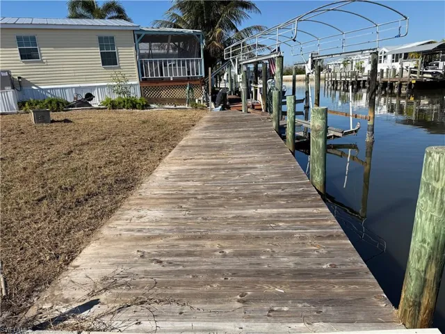 Dock with boat lift, a water view, and a sunroom