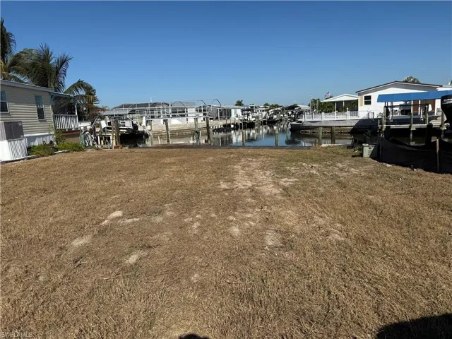 Dock area featuring a water view, boat lift, and a yard
