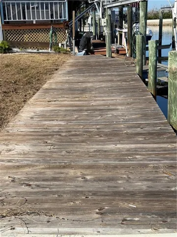 Dock area with boat lift, a water view, and a sunroom