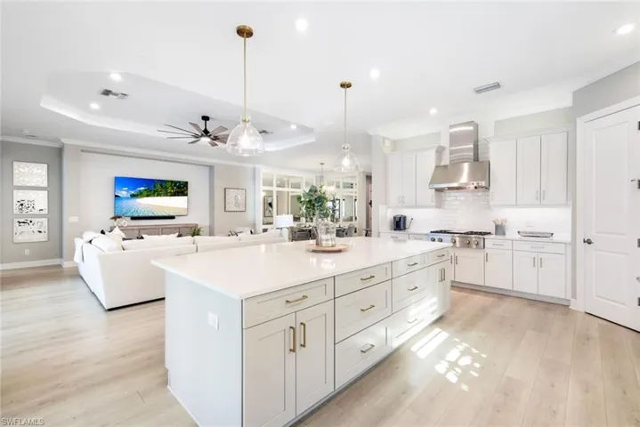 Kitchen featuring hanging light fixtures, open floor plan, a kitchen island, light wood-style floors, and ornamental molding