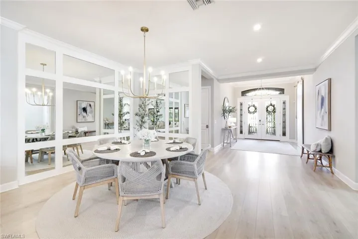 Dining area featuring a chandelier, french doors, light wood-style floors, crown molding, and recessed lighting