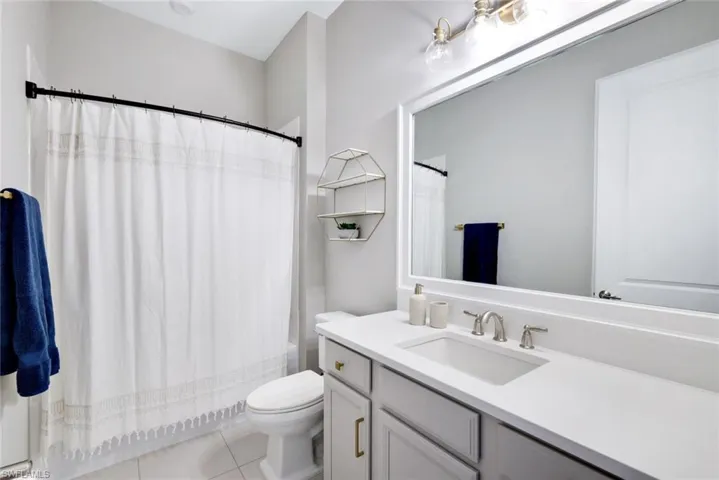 Full bath featuring vanity, shower / bath combo, and light tile patterned flooring