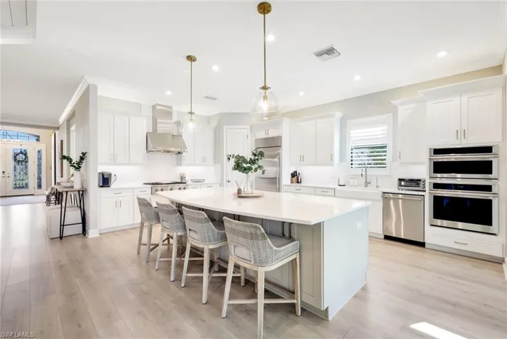 Kitchen featuring a breakfast bar, white cabinets, a center island, decorative light fixtures, and crown molding