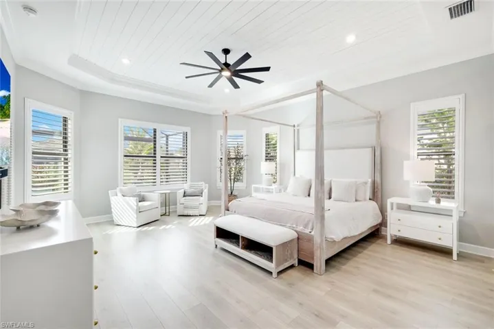 Bedroom with light wood-style flooring, ceiling fan, wooden ceiling, and a tray ceiling