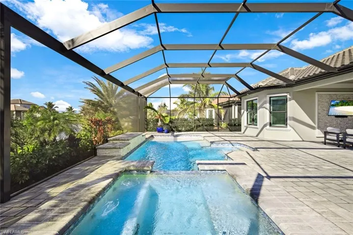 View of pool featuring a sunroom, a patio, a pool with connected hot tub, and a lanai
