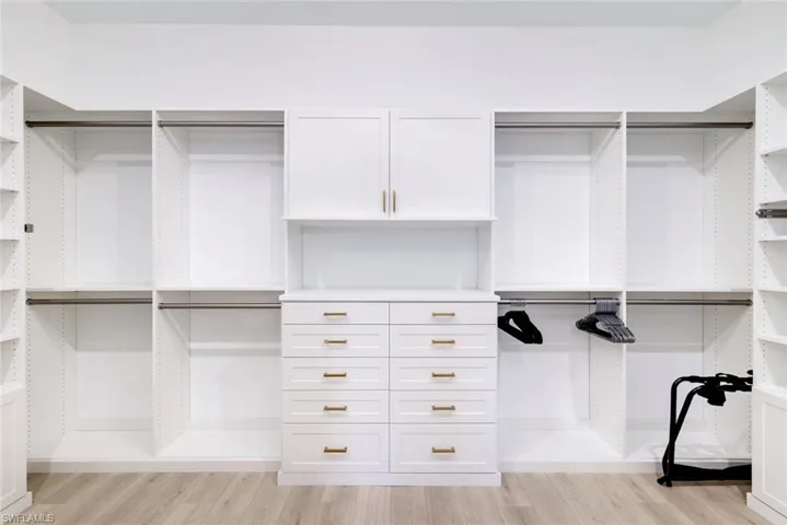 Walk in closet with light wood finished floors