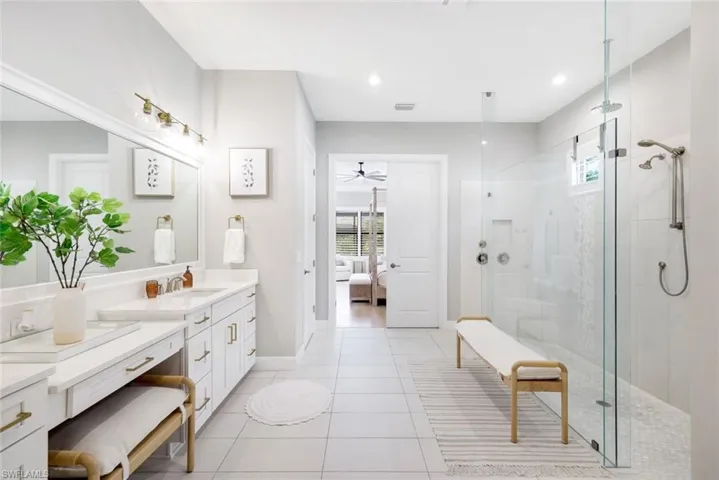 Ensuite bathroom with plenty of natural light, vanity, a shower stall, and light tile patterned flooring