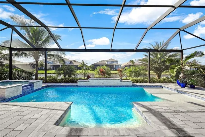 View of pool with a sunroom, a lanai, a pool with connected hot tub, and a patio area
