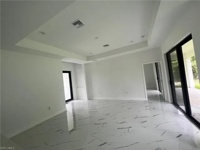 Spare room featuring a wealth of natural light, a tray ceiling, and light tile floors