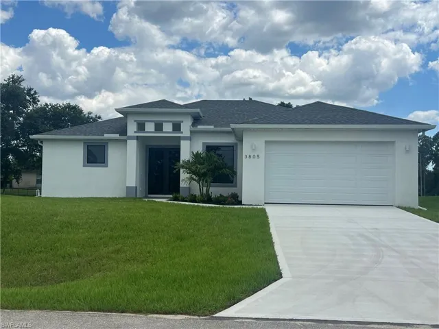 View of front facade featuring a front yard and a garage