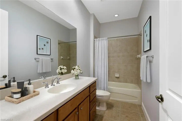 Full bathroom featuring shower / bathtub combination with curtain, tile flooring, vanity, and toilet
