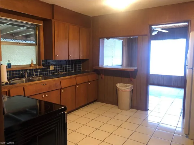 Kitchen with black stove, plenty of natural light, and tile floors