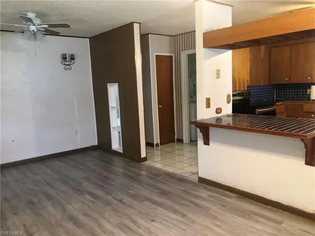 Living room featuring light wood-style flooring, a breakfast bar, and ceiling fan