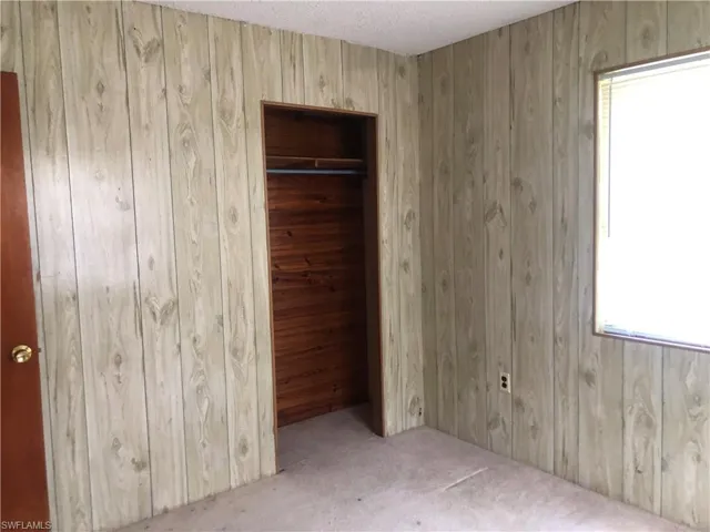 Unfurnished bedroom featuring wood paneling walls and cedar lined closet