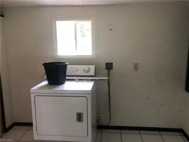 Laundry room featuring washer / dryer, light tile patterned floors, and a textured ceiling