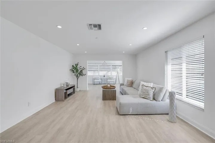 Living room with light vinyl/ wood-style floors. Plenty of natural light.