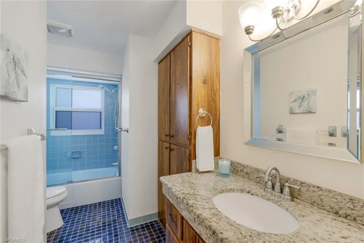 Full guest bathroom with vanity, tile patterned floors, and combined bath / shower with glass door.
