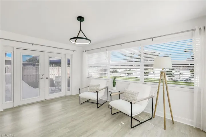 Extra multi-purpose area with impact windows & french doors to the patio, light wood-type flooring, and a wealth of natural light! Ideas for use -  family room, dining area, or office space.