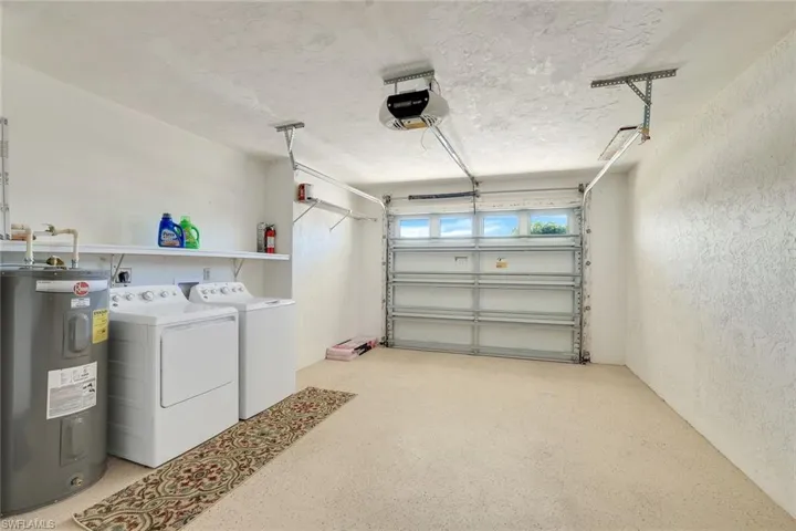 Garage with a garage door opener, water heater, and washing machine and dryer.