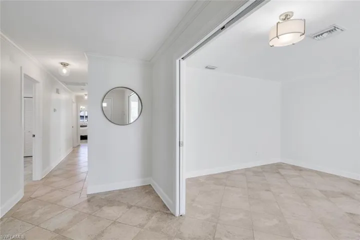 Front hall featuring crown molding. Large den/ 3rd bedroom to right with pocket french doors.
