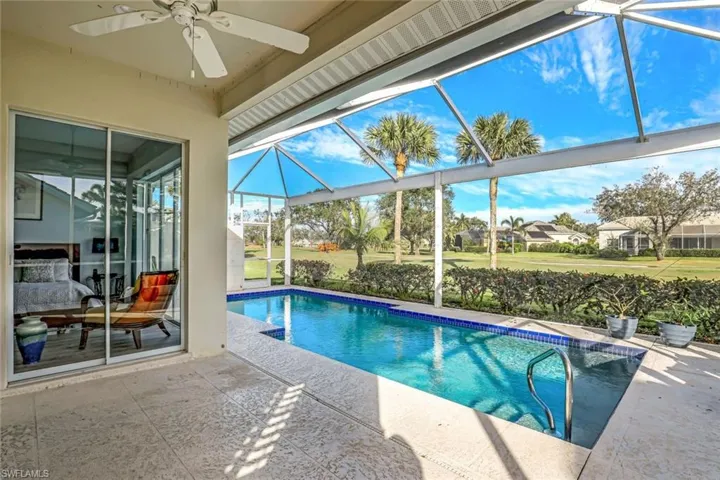 View of swimming pool featuring ceiling fan, a patio area, and glass enclosure