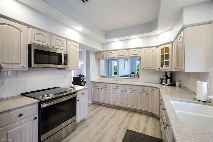 Kitchen with decorative backsplash, stainless steel appliances, and light hardwood / wood-style flooring