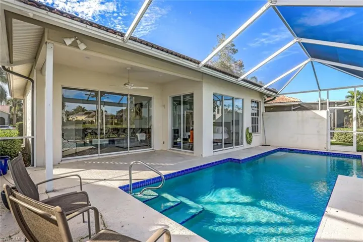 View of pool featuring ceiling fan, a patio area, and glass enclosure